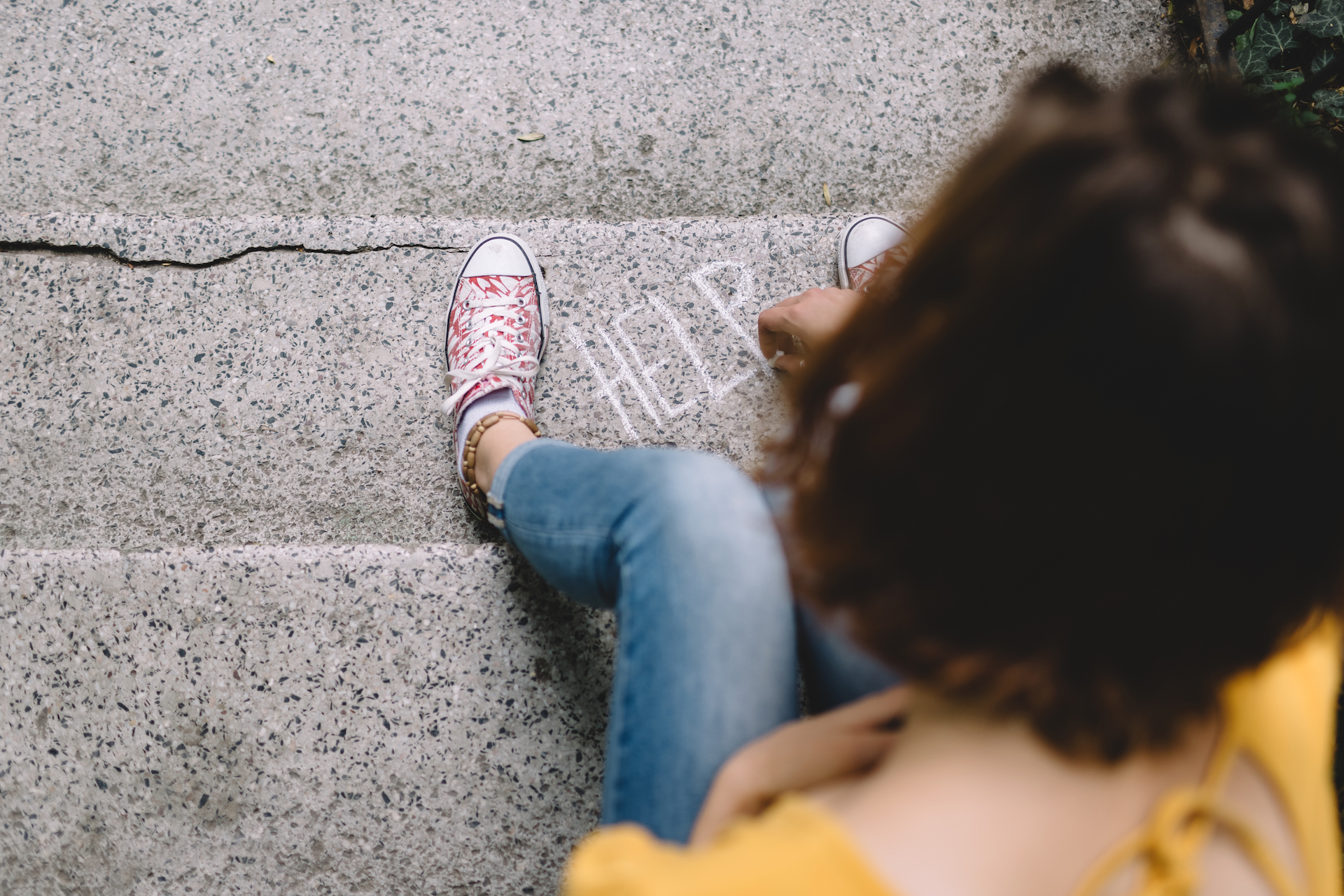 Teen writes on I need help on sidewalk during suicide prevention month.